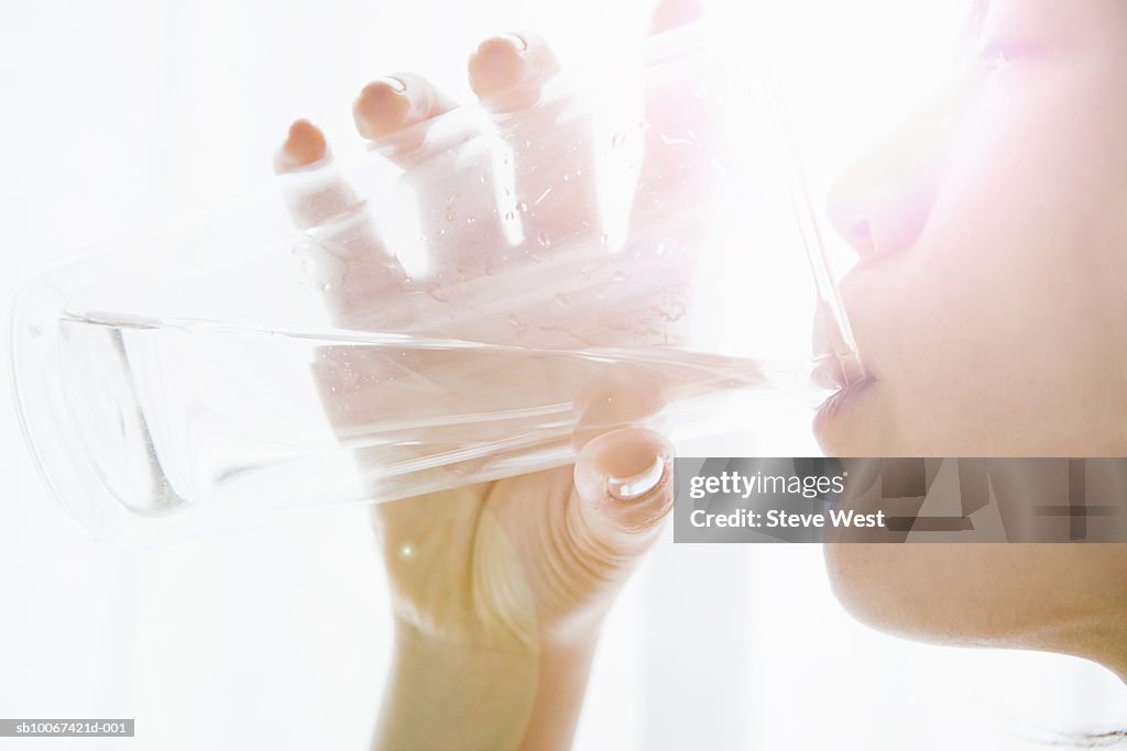 Woman drinking water from glass, close-up, profile