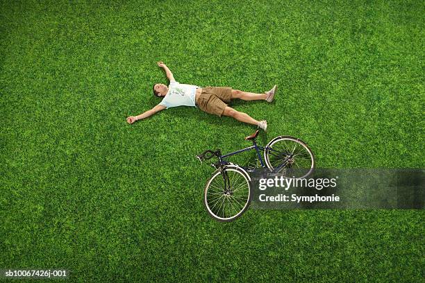 young man lying on grass next to bicycle, elevated view - lying down top view stock pictures, royalty-free photos & images