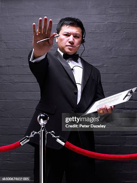 doorman standing behind rope barrier, gesturing, portrait - bouncer stock pictures, royalty-free photos & images