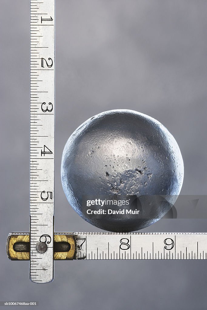 Metal sphere on wooden folding ruler, close up, studio shot