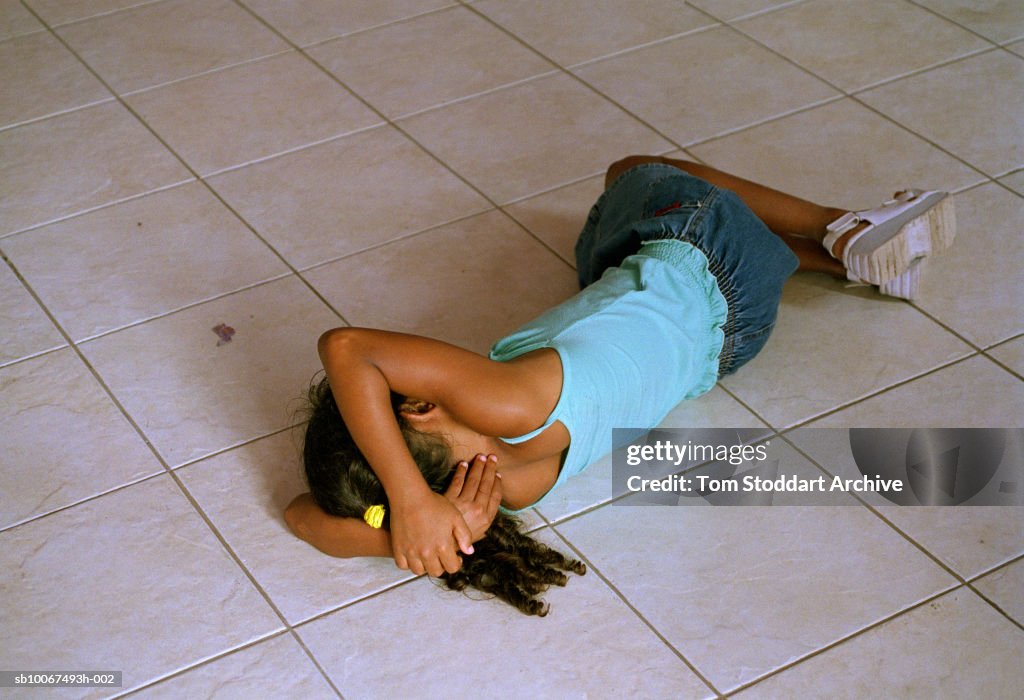 Brazil, Rio de Janeiro, Leblon district, girl (8-9) sleeping on tiled floor in homeless shelter