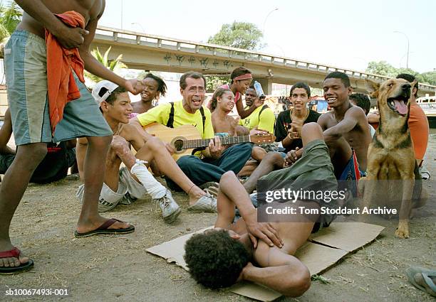 Street children enjoy a rare few minutes of fun as they sing songs with a guitar playing aid worker Georges Paixao who is from the San Martino...