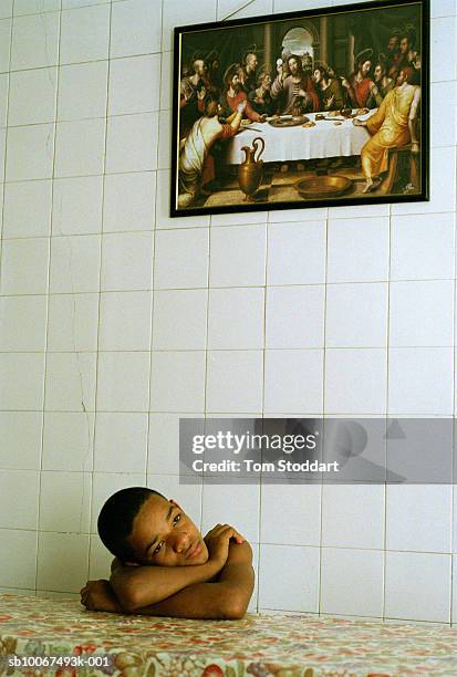 Young boy rescued from the streets of Rio De Janeiro and given sanctuary at a childrens home, pictured beneath a painting of Christ and his disciples...