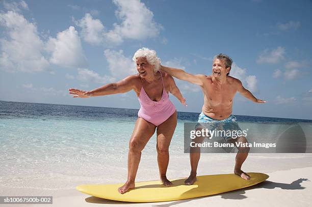 senior couple standing on surfboard - badkläder bildbanksfoton och bilder