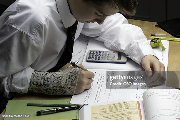 school boy (12-13 years) with arm in cast writing at desk, mid section - 12 13 years 個照片及圖片檔