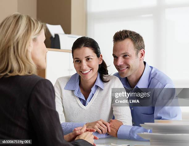 mid adult couple talking with insurance agent in office, smiling - pareja de mediana edad fotografías e imágenes de stock