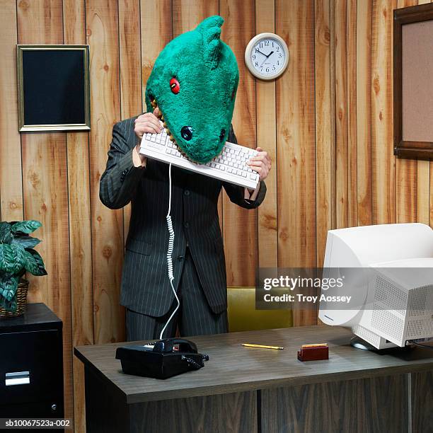 dinosaur in office eating computer keyboard - bizarre office stock pictures, royalty-free photos & images