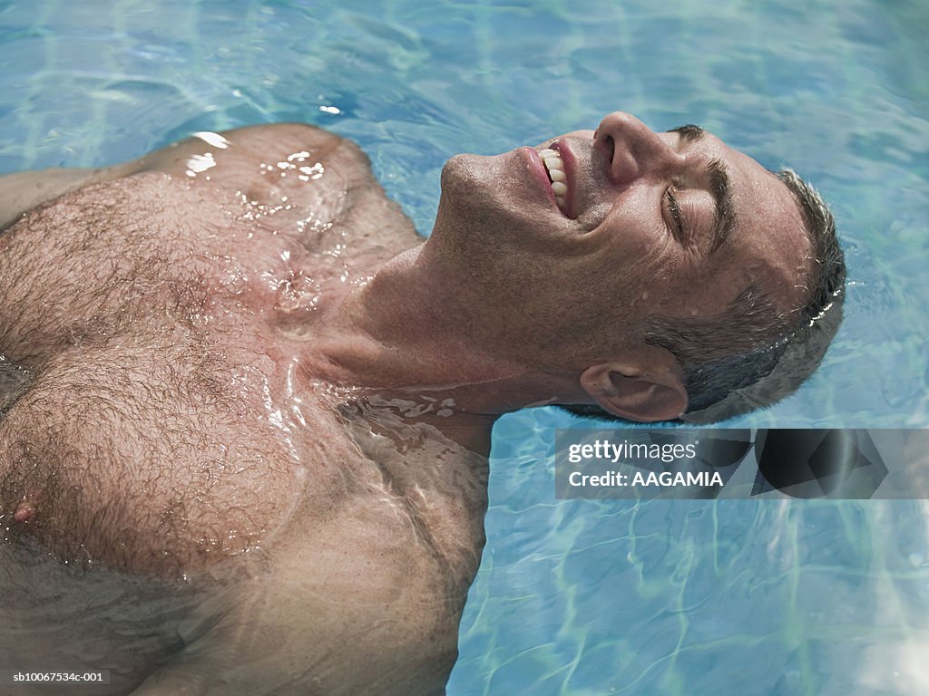 Mature man floating on water in swimming pool, close-up