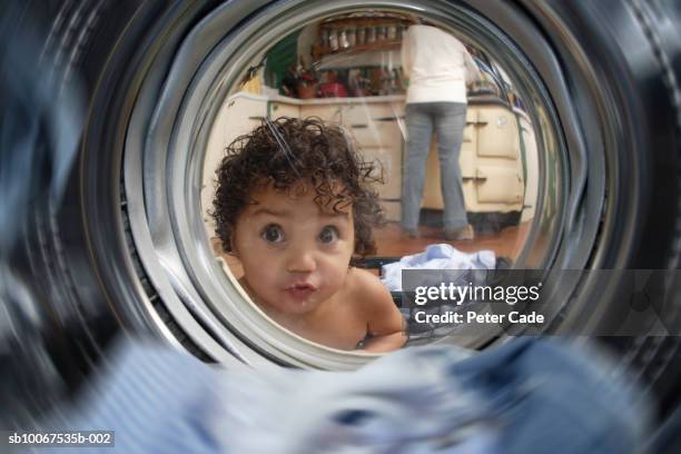 girl (21-24 months) looking in washing machine, mother in background - washing machine stock pictures, royalty-free photos & images