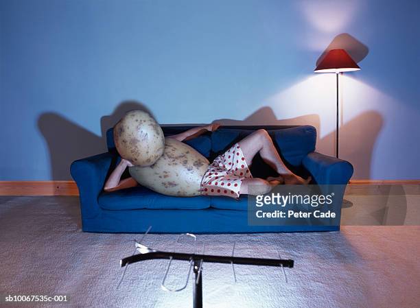 man in potato costume lying on sofa watching television - couch potato imagens e fotografias de stock