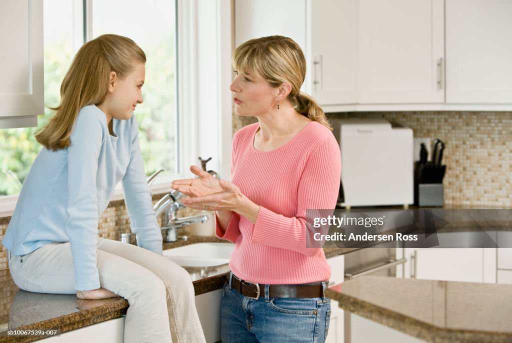 Mother and daughter (10-11) discussing in kitchen