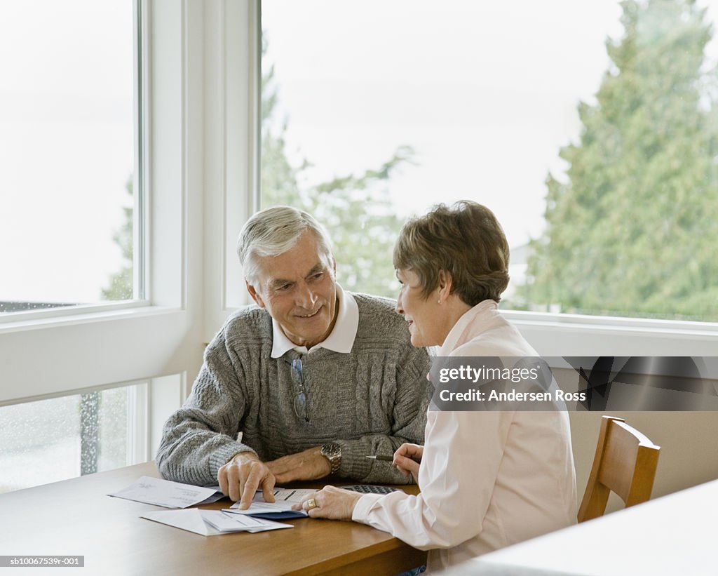 Senior couple holding bills, smiling