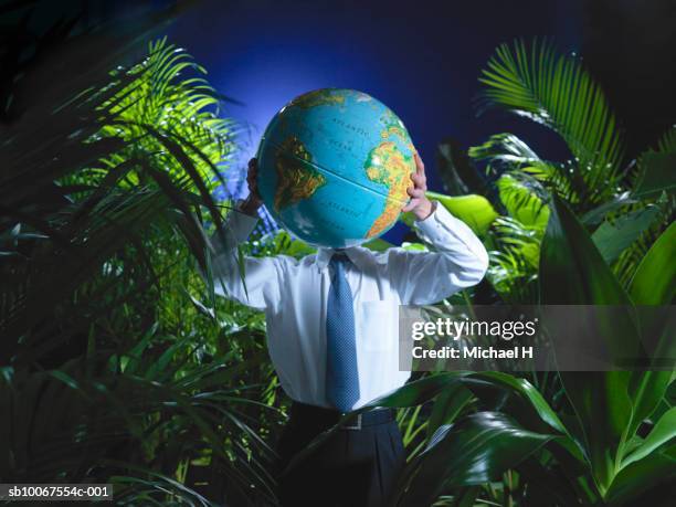 man holding globe in jungle - globe businessman stockfoto's en -beelden