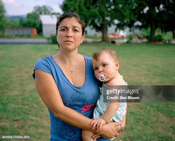 mother holding baby girl (15-18 months) in lawn, portrait - anxious looking to camera fotografías e imágenes de stock