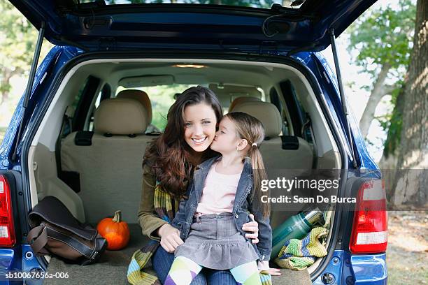 mother and daughter (6-7) sitting in car trunk - soccer mum stock-fotos und bilder