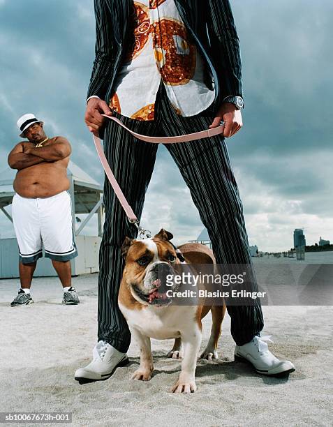 person holding bulldog on beach, man watching in background - fat guy on beach photos et images de collection