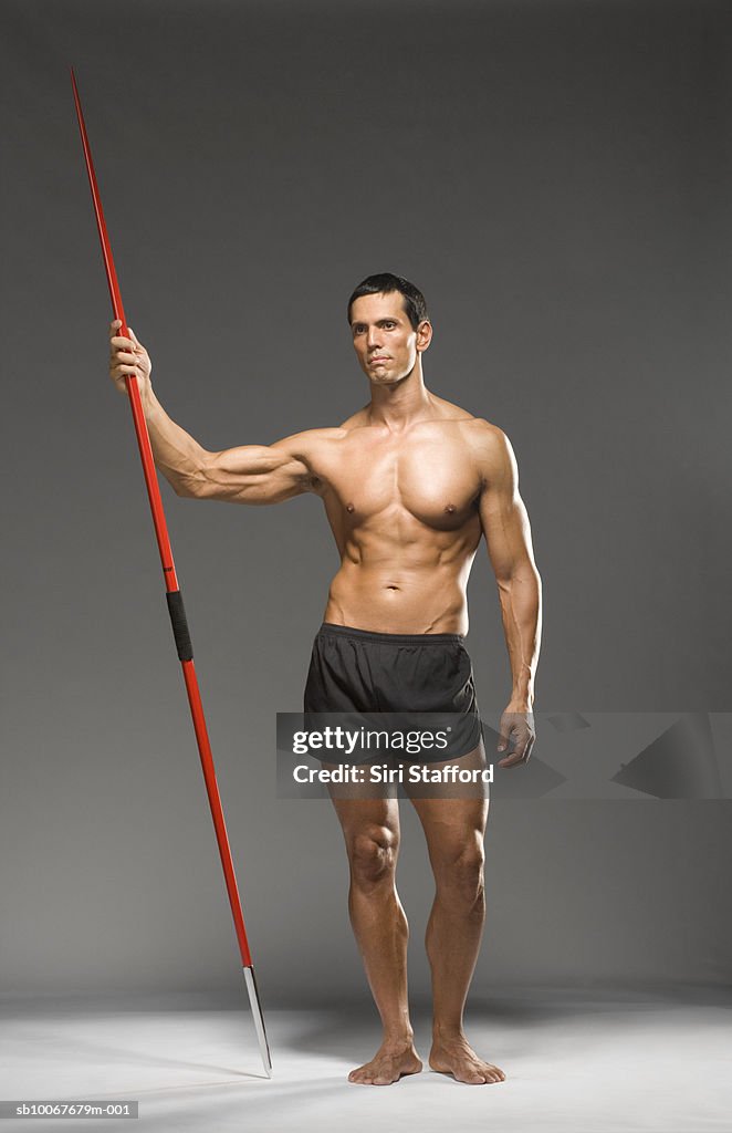 Male athlete holding javelin, studio shot