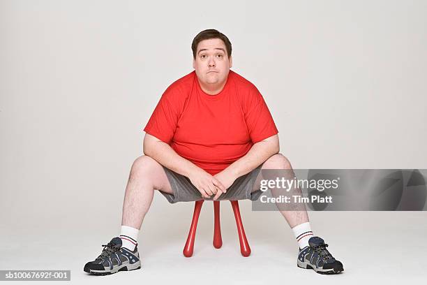 overweight man sitting on stool, portrait - tabouret photos et images de collection