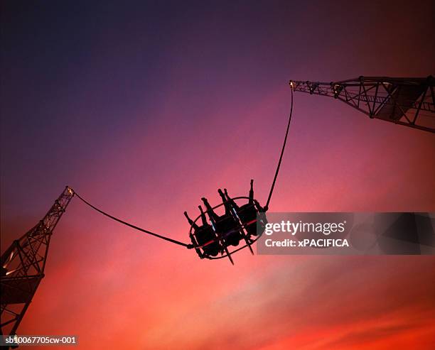 singapore, silhouettes of three people on bungee slingshot at sunset, directly below - bunjee jumping stock-fotos und bilder