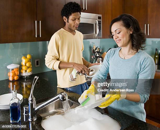 couple washing dishes in kitchen, smiling - couples showering stock-fotos und bilder