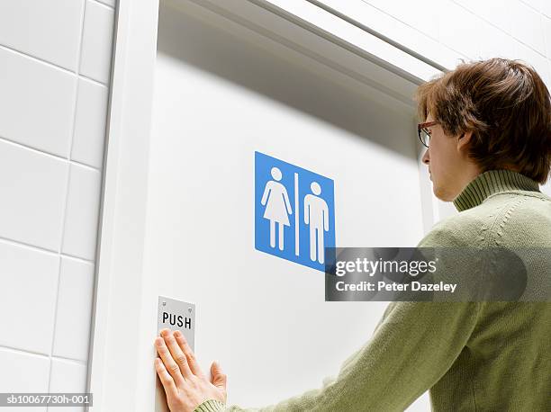 man pushing toilet door - restroom door stockfoto's en -beelden