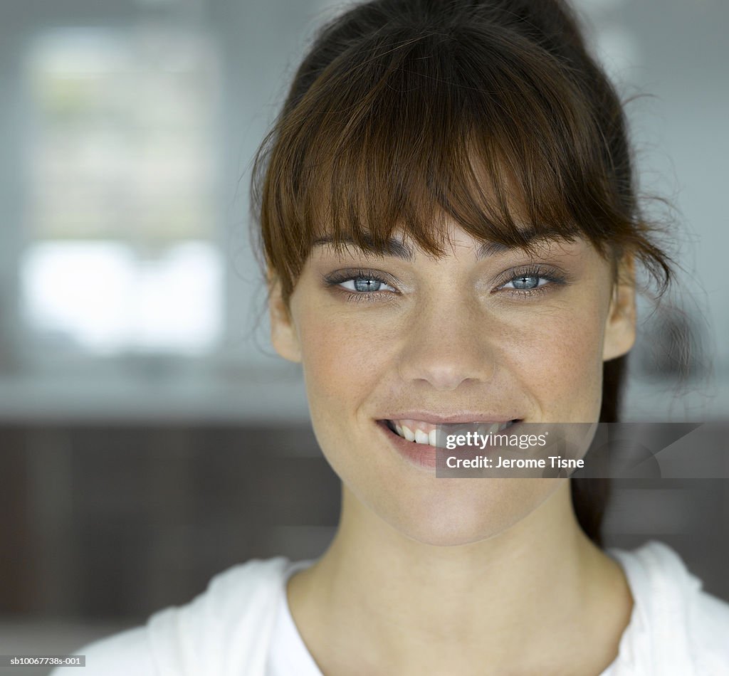 Young woman smiling, indoors, portrait