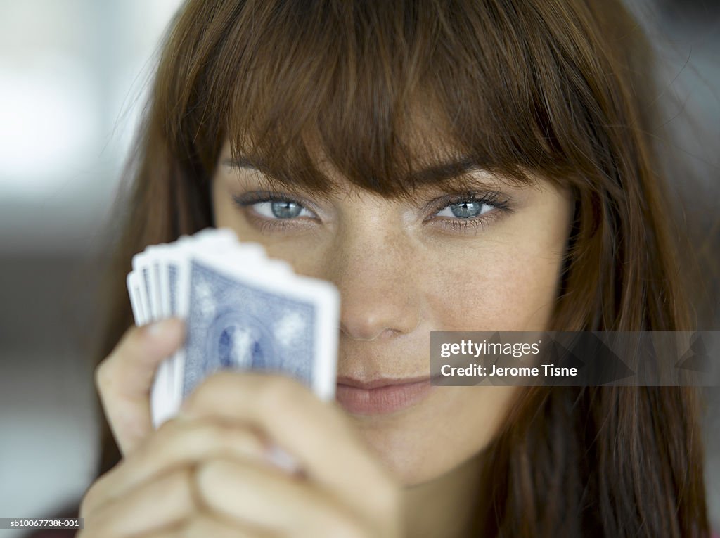 Young woman holding playing cards, smiling, portrait