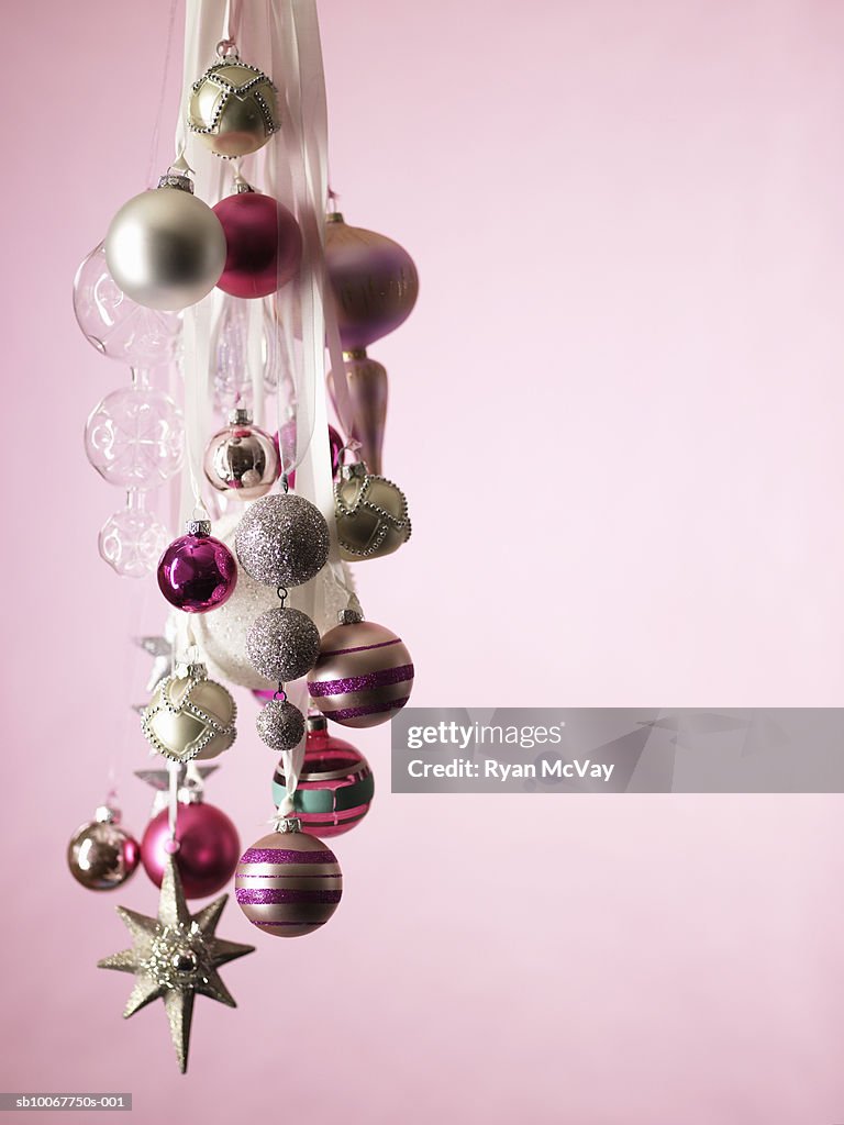 Christmas ornaments hanging against pink background