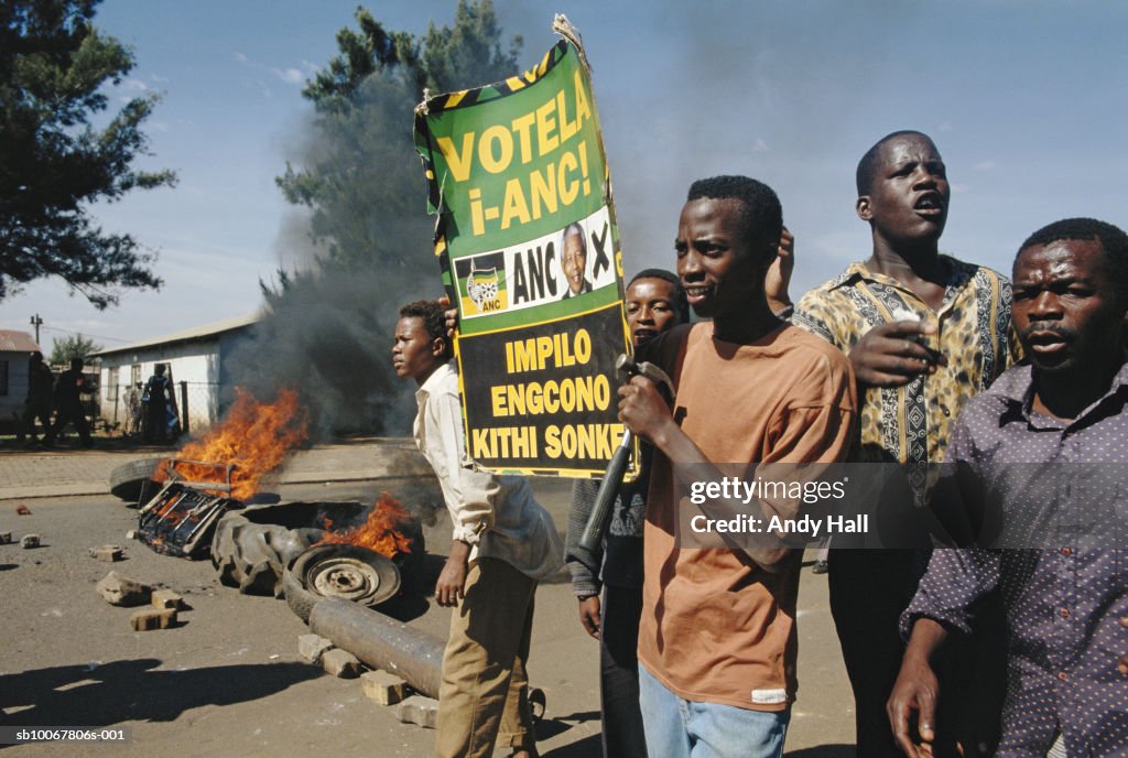 South Africa, Tokoza, group of men with placard, car burning in background