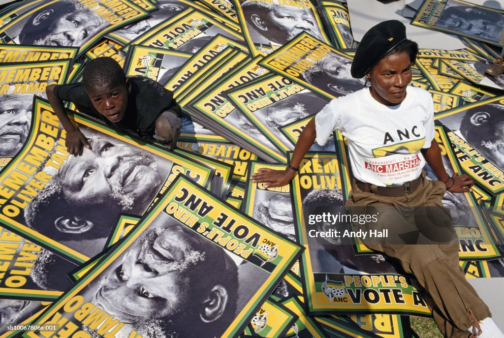 South Africa, Soweto,  African National Congress Rally, woman and boy (10-11) sitting on placards