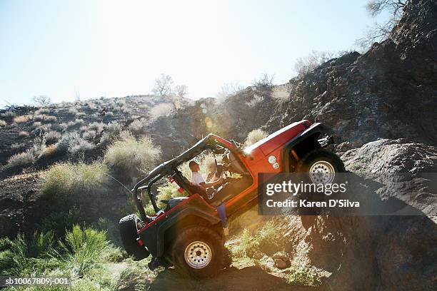 man driving off-road vehicle over rocks - off road stock-fotos und bilder