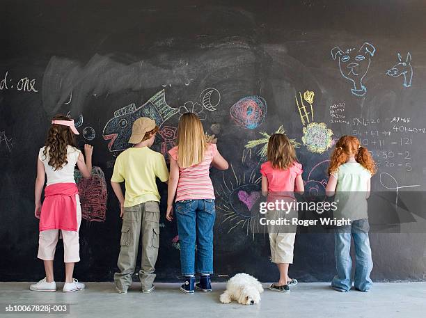 group of children (7-9 years) drawing on chalkboard, rear view - chalkboard drawing stock-fotos und bilder