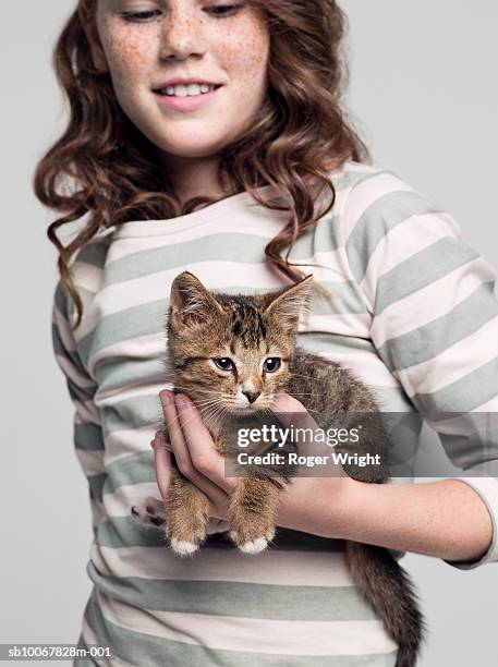 girl (8-9 years) carrying kitten in hand, studio shot - cat studio stock pictures, royalty-free photos & images