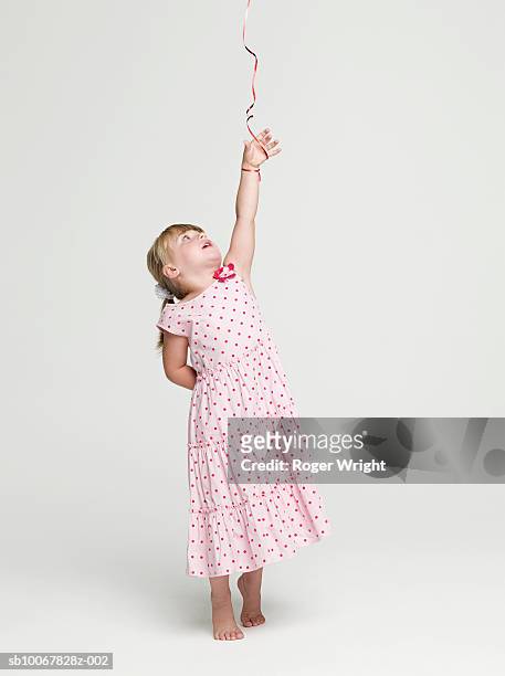 girl (2-3 years) with balloon string tied to hand, studio shot - child reaching stock pictures, royalty-free photos & images