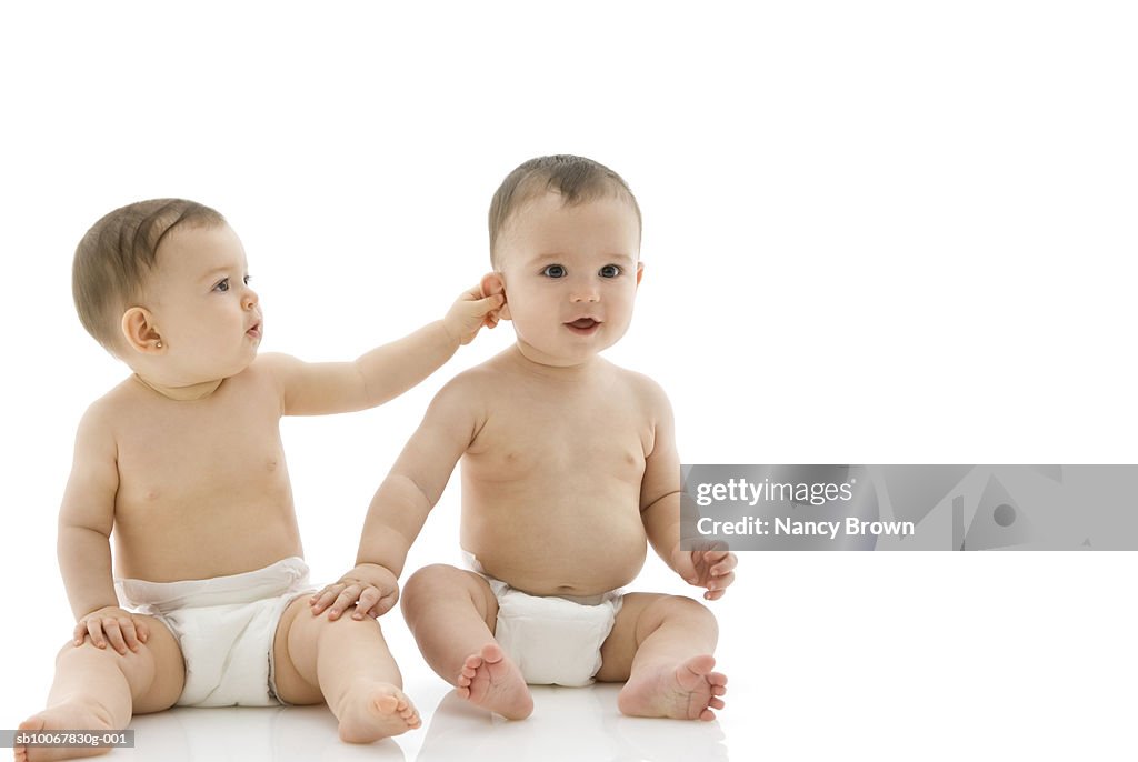 Two baby boys (6-11 months) sitting on white background