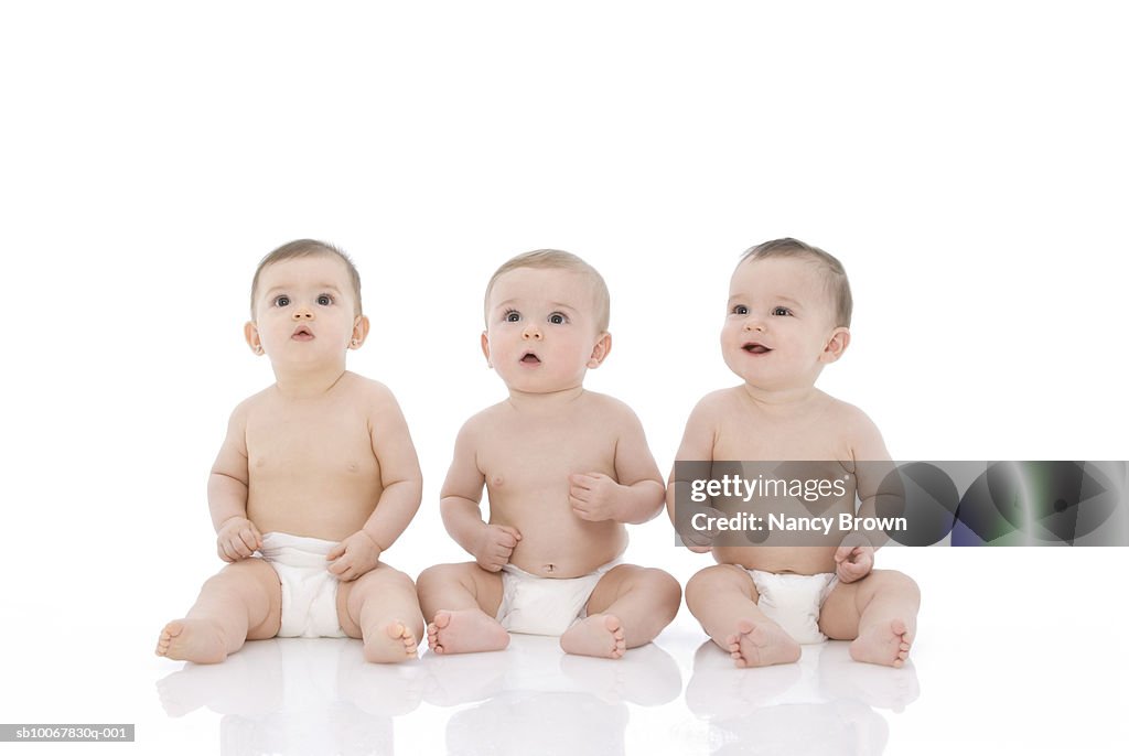 Three baby boys (6-11 months) sitting on white background