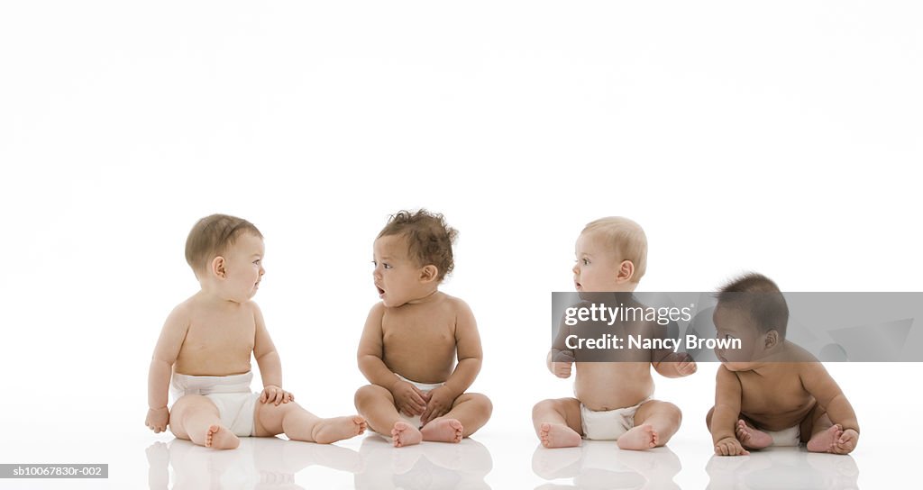 Four baby boys (6-11 months) sitting on white background