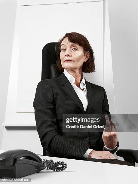 business woman making hand gesture sitting behind desk, portrait - doigt dhonneur stock pictures, royalty-free photos & images