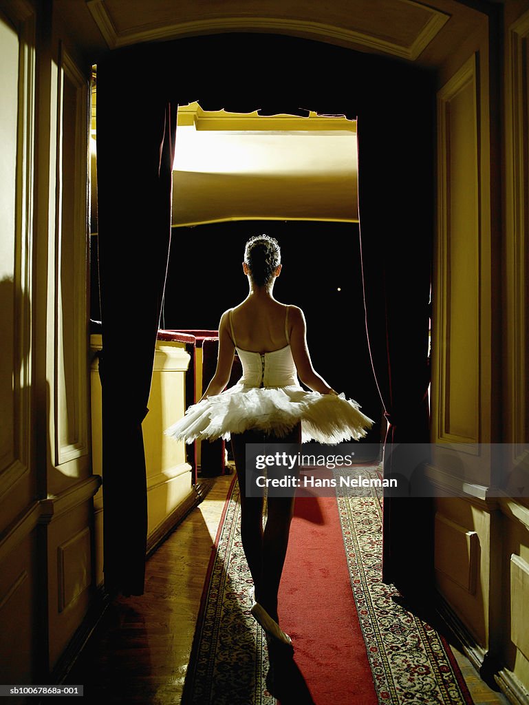 Teenage ballerina (14-15) waiting in wings, rear view