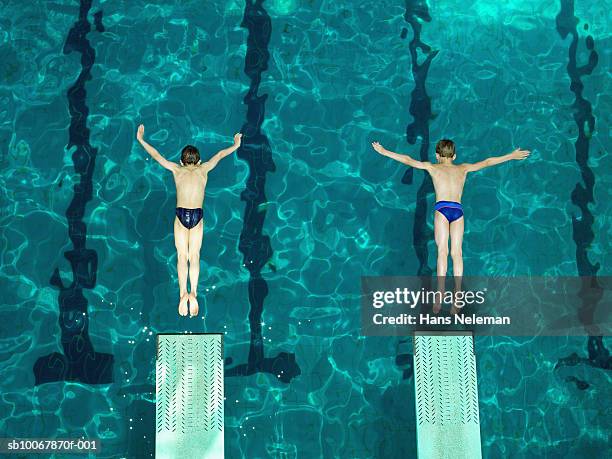 two boys (8-9) diving off of starting block, elevated view - symmetry stockfoto's en -beelden