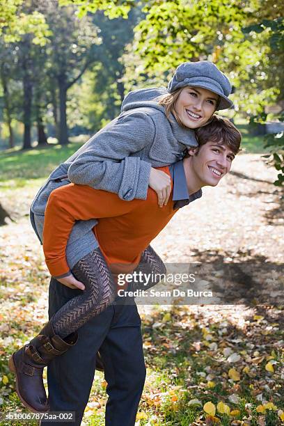 man giving woman piggyback ride, smiling - couple central park stock pictures, royalty-free photos & images