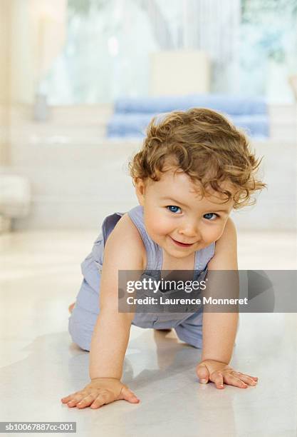 baby boy (9-12 months) crawling on floor, smiling, portrait - crawling stock-fotos und bilder