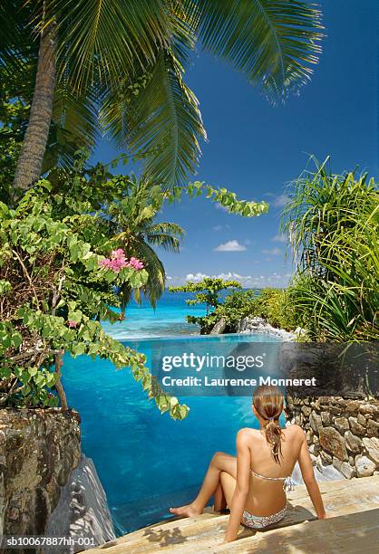 teenage girl (13-14) wearing bikini sitting on steps by swimming pool, rear view - fregate stock pictures, royalty-free photos & images