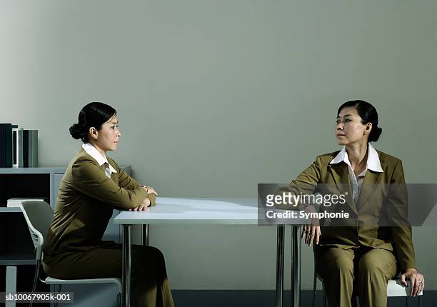 businesswoman looking at duplicate sitting at table in office (digital composite) - asian twins photos et images de collection