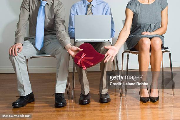 man handing woman heart shape gift around oblivious co-worker - oblivious coworker stock pictures, royalty-free photos & images
