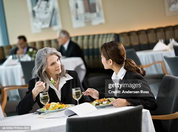 mature and mid adult business women talking during lunch - dinner business stock-fotos und bilder