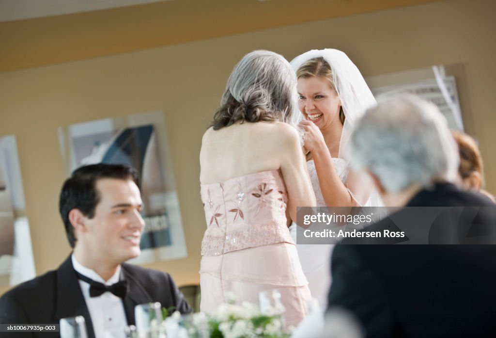 Bride talking with mother and groom with father during wedding party