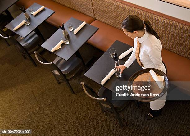 female waitress setting table at restaurant, elevated view - table dressée photos et images de collection