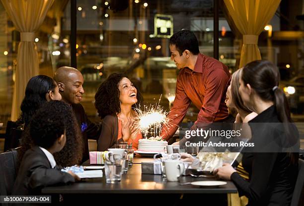 waiter brings birthday cake for woman during dinner - geburtstagstorte stock-fotos und bilder