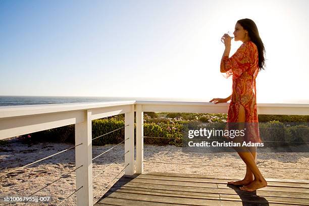 young woman on veranda, drinking water, side view - standing water fotografías e imágenes de stock